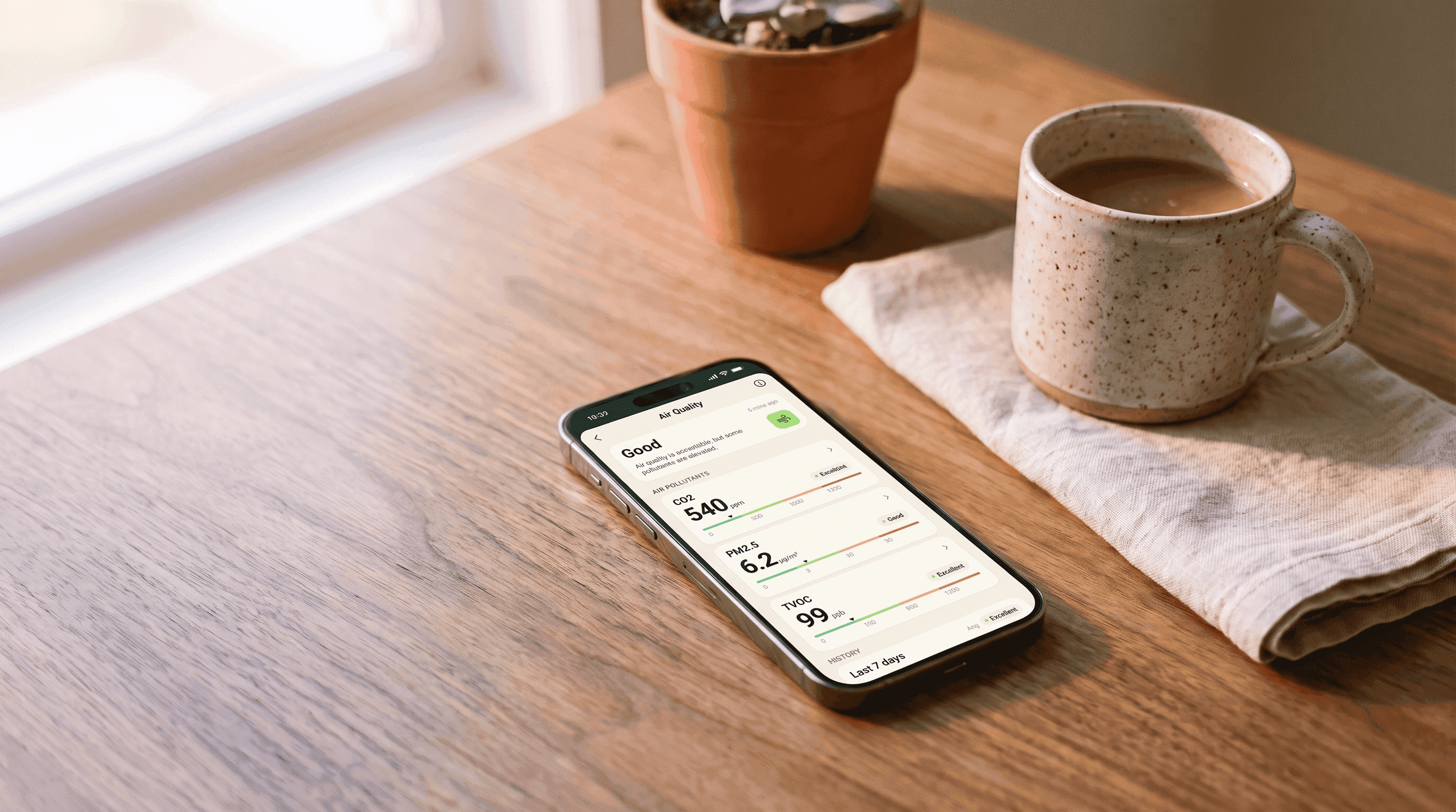 The Jetson Home app open to the Air Quality screen on a phone resting on a sunlit kitchen table