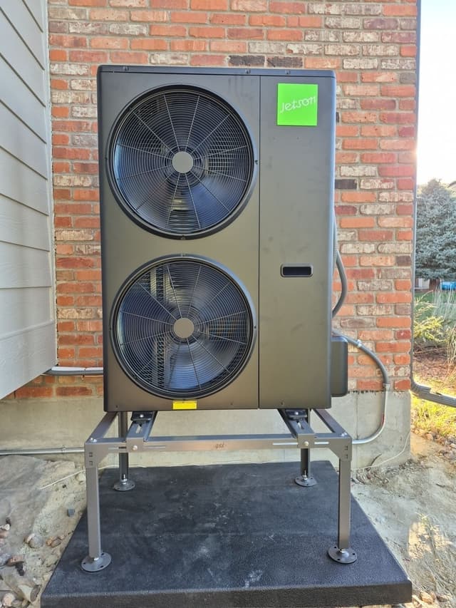 Jetson Air 5-ton central ducted heat pump condenser unit mounted against a red brick wall at a home in Aurora.