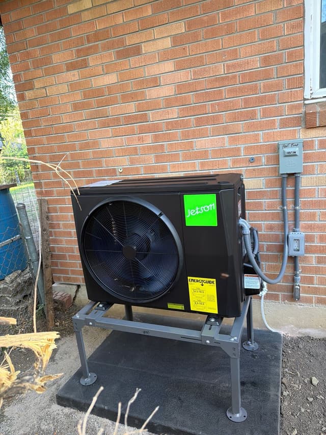 2-ton Jetson Air central ducted heat pump mounted against a brick exterior wall of a Boulder home, with conduit running up to a disconnect box and electrical panel.