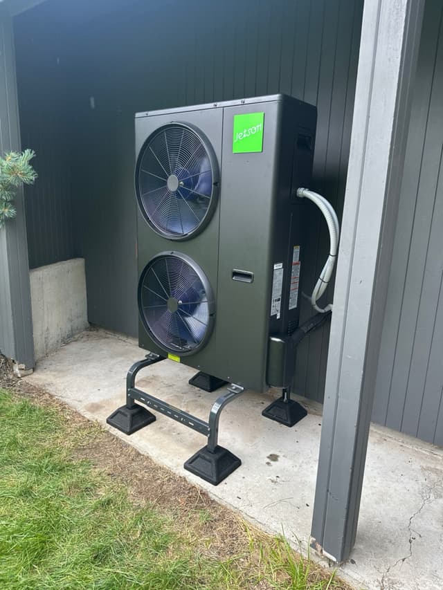 Jetson Air 4-ton dual-fan heat pump condenser installed against dark vertical siding at a home in Carlisle, MA.
