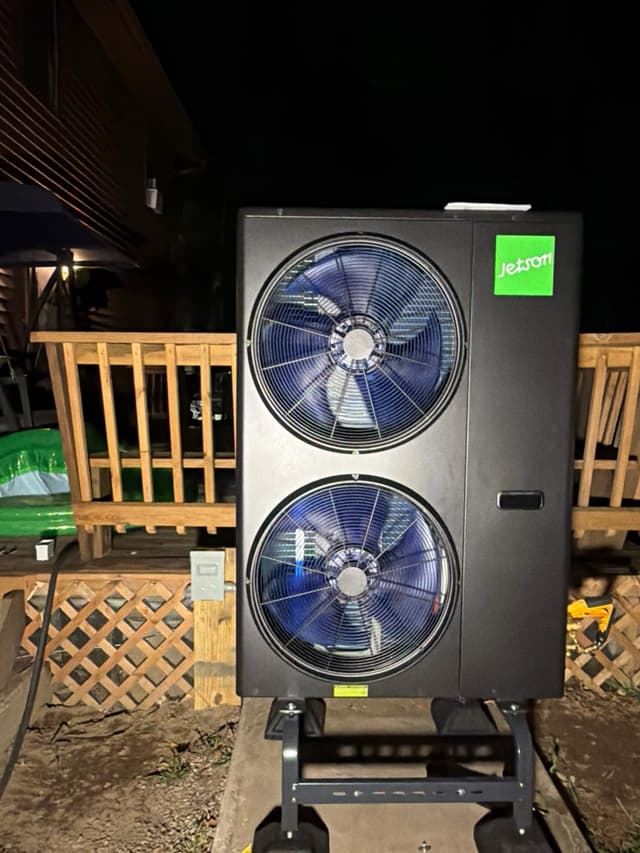 Black Jetson Air 5-ton heat pump unit with dual fan faces beside a wooden deck at a home in Danvers, MA.