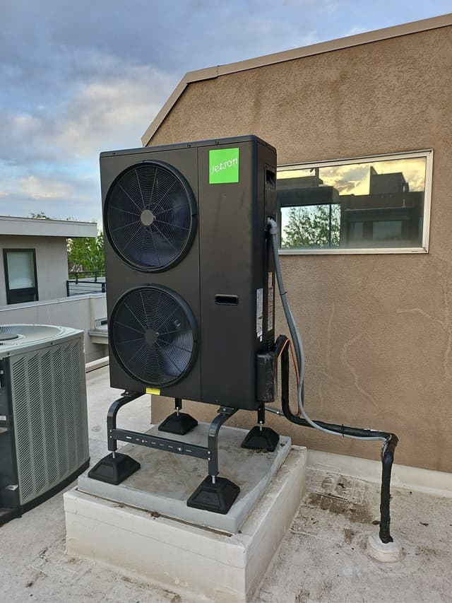4-ton Jetson Air ducted heat pump condenser mounted on a raised concrete pad on a flat rooftop in Denver, CO, with conduit and refrigerant lines routed neatly along the surface.