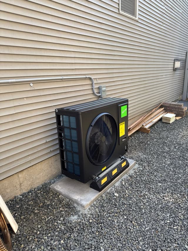 Black Jetson Air 3-ton heat pump condenser installed against light grey vinyl siding on a Langley home, with metal conduit running to a disconnect box above the unit.