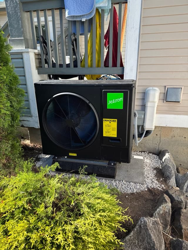 Jetson Air 3-ton central ducted heat pump condenser installed against the side of a residential home in Walnut Grove, Langley Township, BC, with line-set conduit and disconnect box visible on the wall.