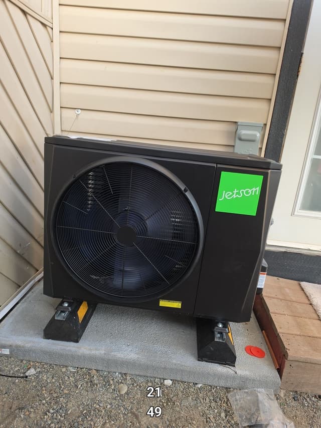 Jetson Air 2-ton central ducted heat pump installed against beige siding on a home in Fern Ridge, Langley, with disconnect box visible on the wall.