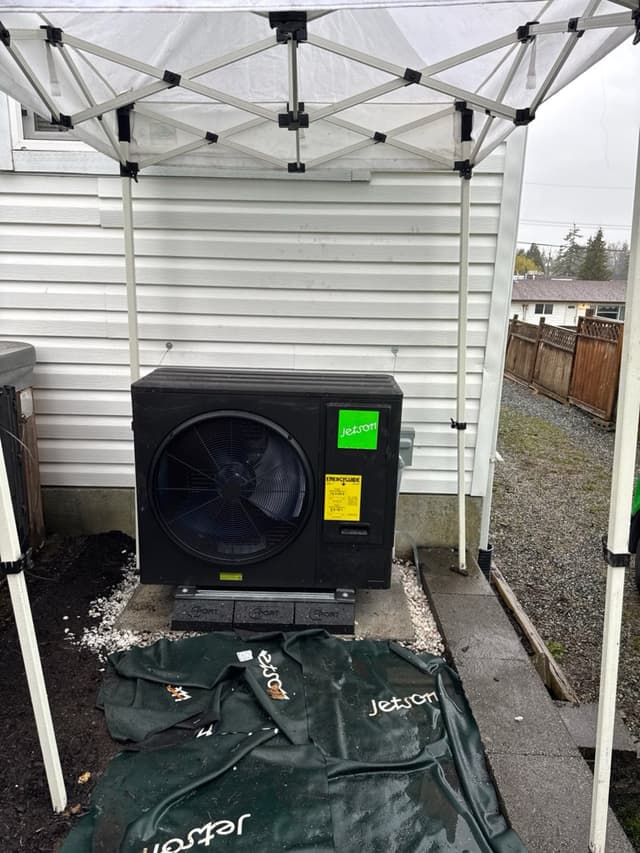 Jetson Air 3-ton central ducted heat pump on a concrete pad with rubber isolation pads against white horizontal siding in Aldergrove, Langley Township, BC.