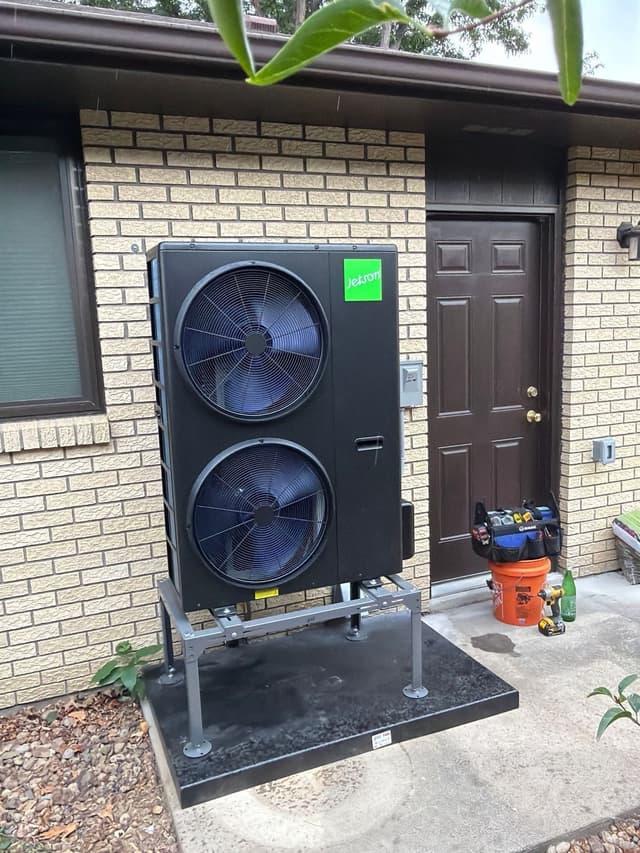 4-ton Jetson Air central ducted heat pump installed against a cream brick wall near a front door in Longmont, Colorado, with crew tools visible beside the unit.