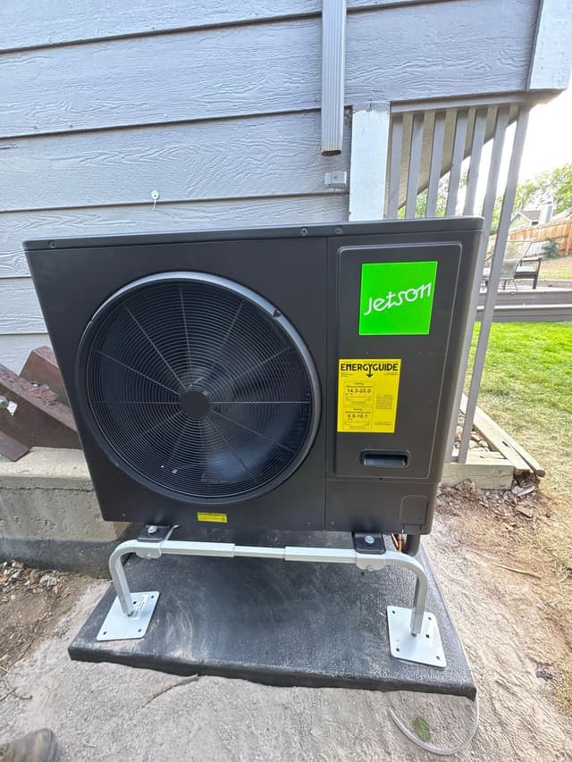 Jetson Air 3-ton central ducted heat pump installed on a concrete pad beside a house in Louisville, CO, with conduit running up the siding and a deck railing visible to the right.