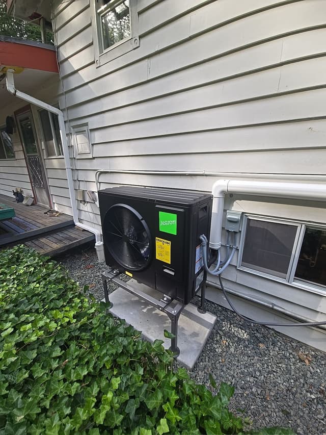 Jetson Air 3-ton central ducted heat pump outdoor unit installed along the side of a grey-sided house in Whonnock, Maple Ridge, with line sets and conduit running neatly toward the home.
