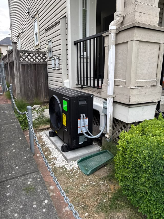 Black Jetson Air 3-ton heat pump condenser installed on a concrete pad with white gravel surround beside a residential home in Clayton Heights, Surrey, BC.
