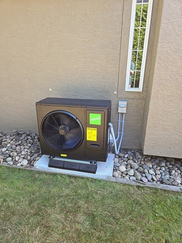 Jetson Air 3-ton central ducted heat pump condenser mounted against a tan stucco exterior wall in Sullivan, Surrey, with conduit and refrigerant lines running neatly into the wall.