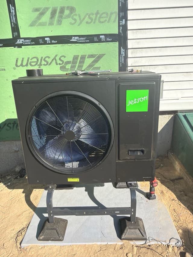 Jetson Air 3-ton central ducted heat pump outdoor unit installed against green ZIP System sheathing and white vinyl siding at a home in Townsend, MA.