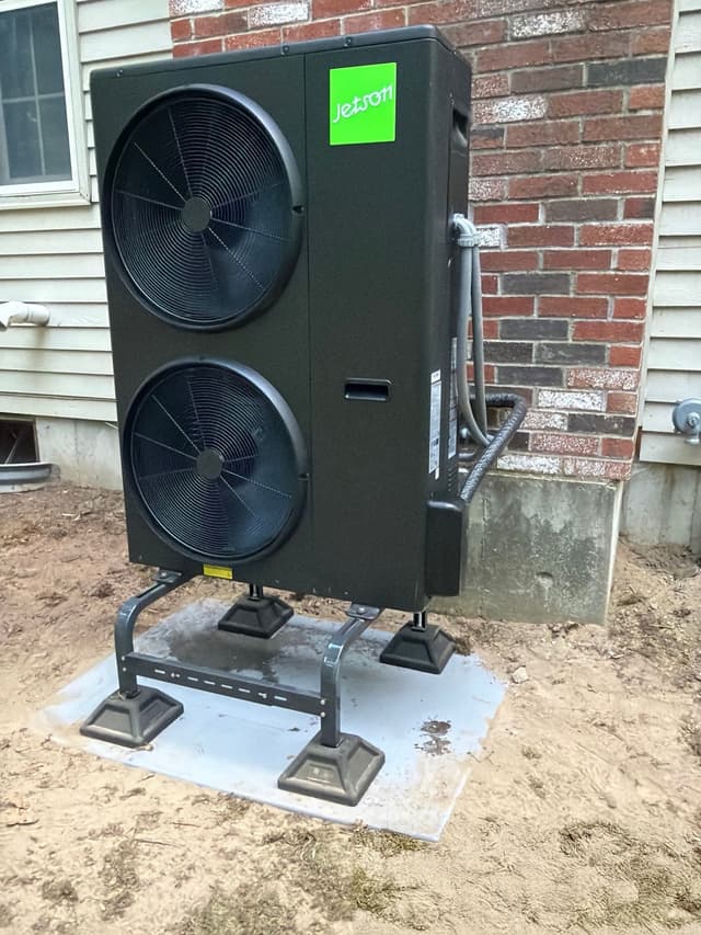 Jetson Air dual-fan 5-ton outdoor heat pump unit installed against a brick foundation and gray vinyl siding at a home in Walpole, MA.