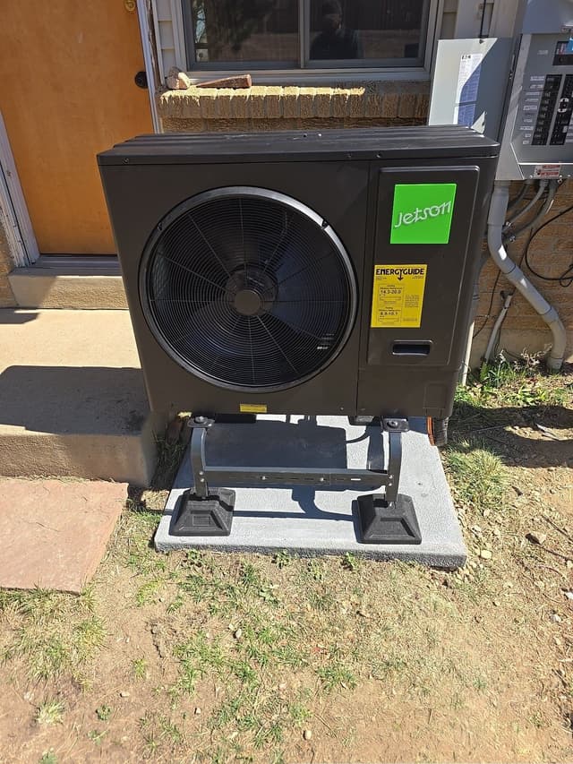3-ton Jetson Air central ducted heat pump installed on a concrete pad with adjustable leg stands against the stucco-and-brick exterior wall of a home in Westminster, CO.