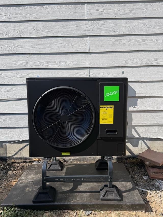 Jetson Air 3-ton heat pump mounted on a black metal stand on a concrete pad against gray lap siding of a home in Westminster, CO.