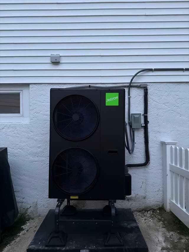 4-ton Jetson Air central ducted heat pump condenser mounted against the stucco-and-siding exterior of a home in White Plains, NY, with electrical conduit running neatly to a disconnect box above.