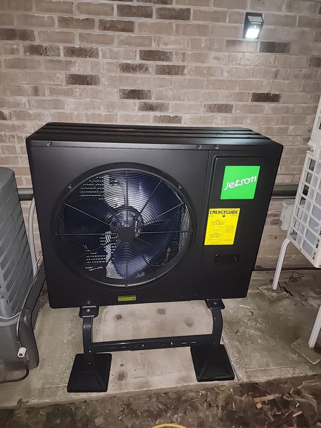 3-ton Jetson Air central ducted heat pump installed against a brick exterior wall in Yonkers, NY, photographed at night under a security light.