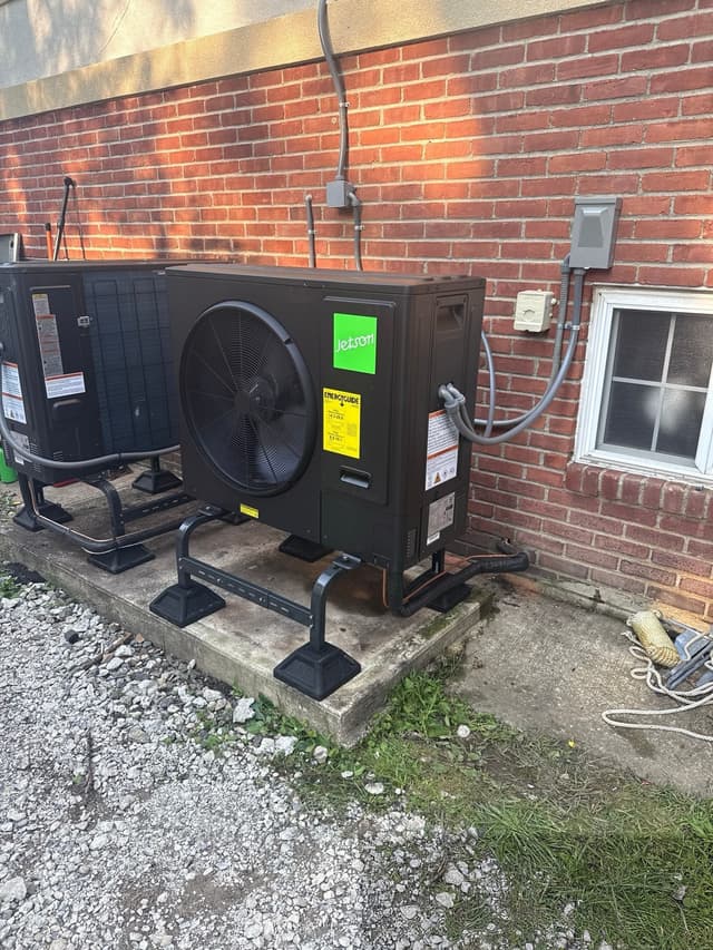 Two black Jetson Air outdoor heat pump units mounted against a red brick wall at a home in Yorktown Heights, NY.