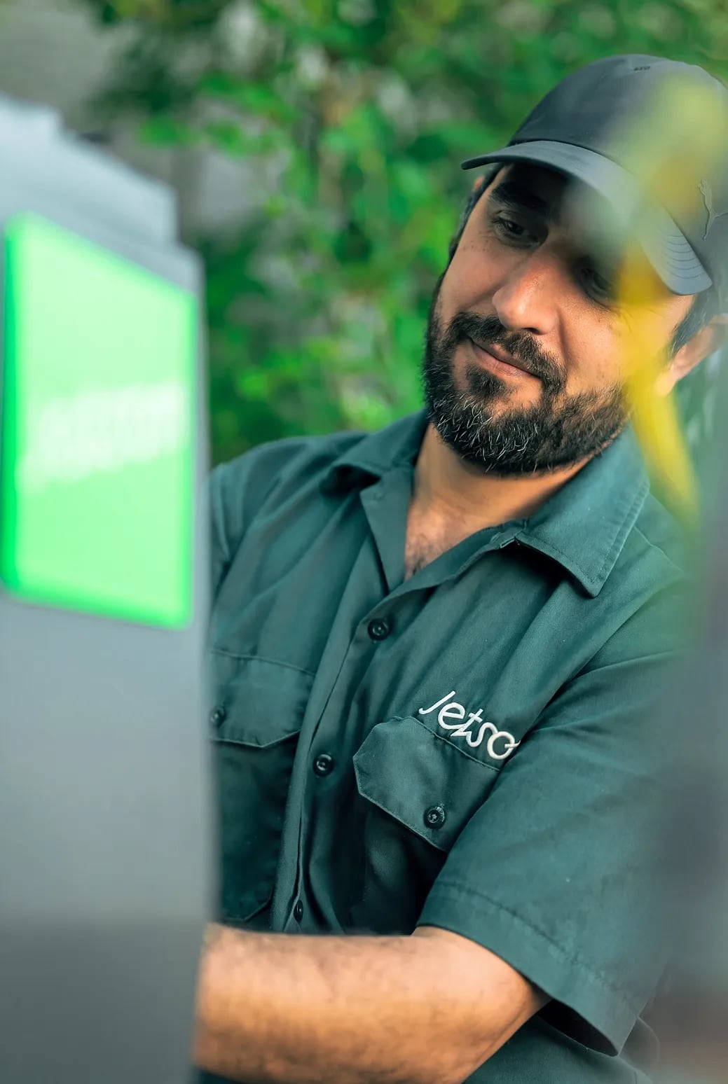 A Jetson technician in uniform smiling beside a Jetson heat pump