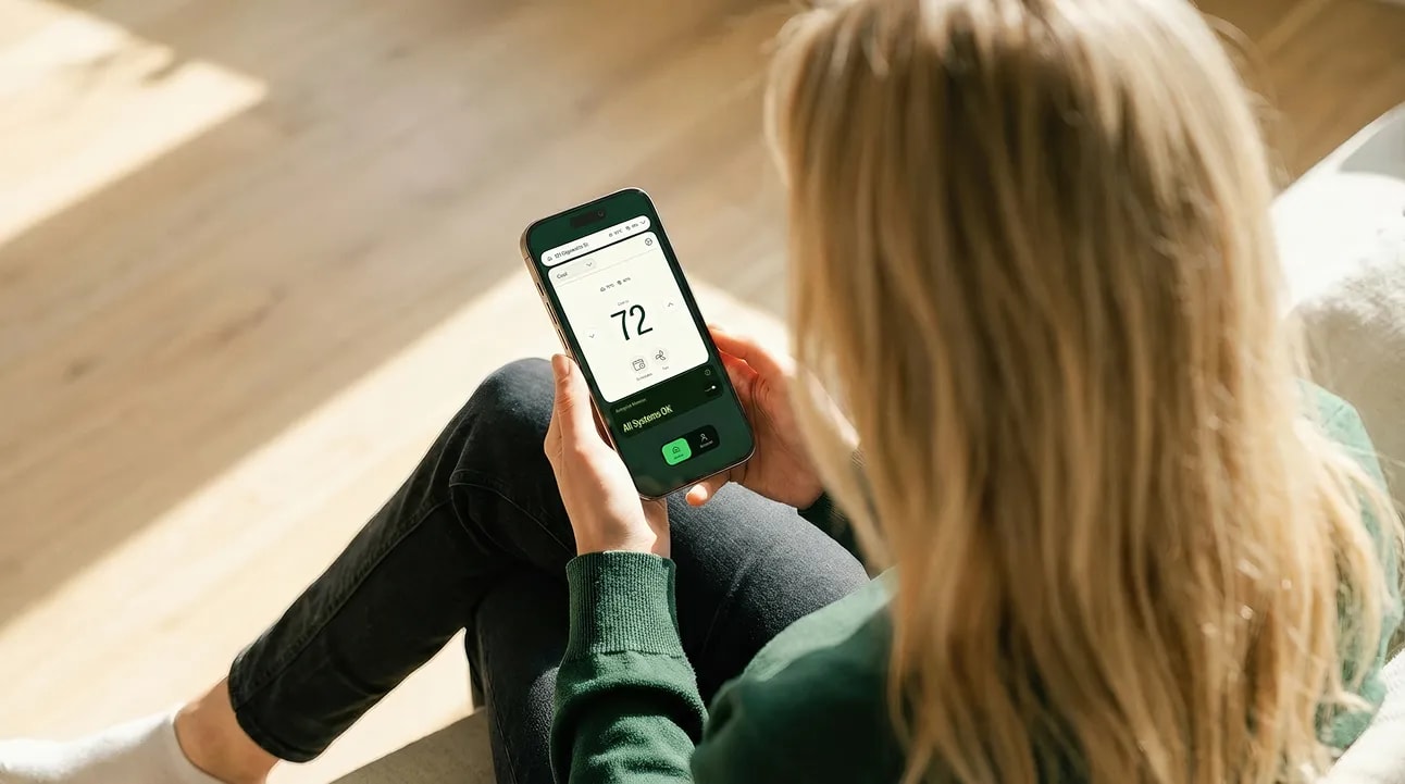 A woman sitting on a sunlit floor checking the Jetson app on her phone