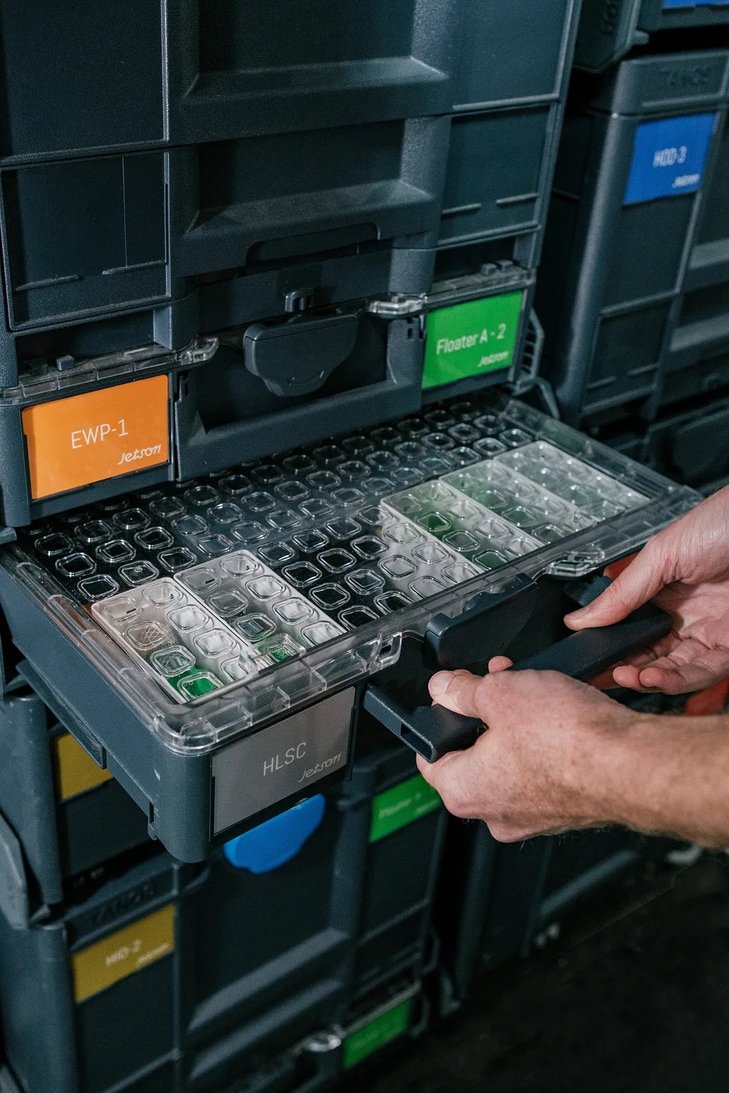 A technician pulling open a drawer of neatly organized, Jetson-labelled parts organizers