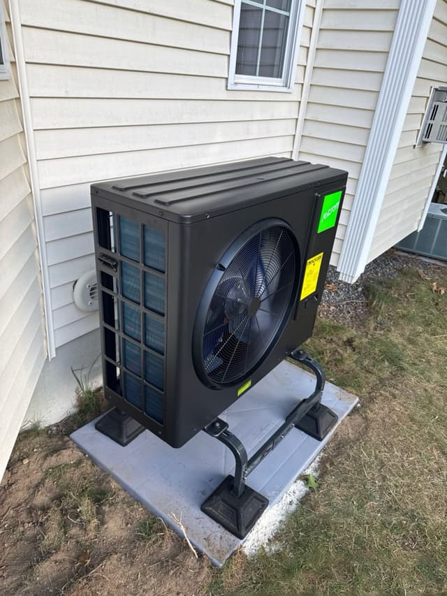 Jetson Air 3-ton outdoor heat pump condenser installed against white vinyl siding on the side of a house in Attleboro, MA.