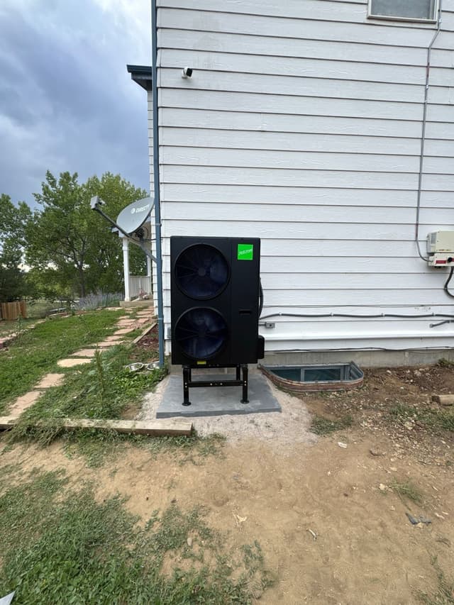A black Jetson Air 4-ton central ducted heat pump installed along the side of a white-sided house in Aurora, with line sets and conduit running neatly to a disconnect box.