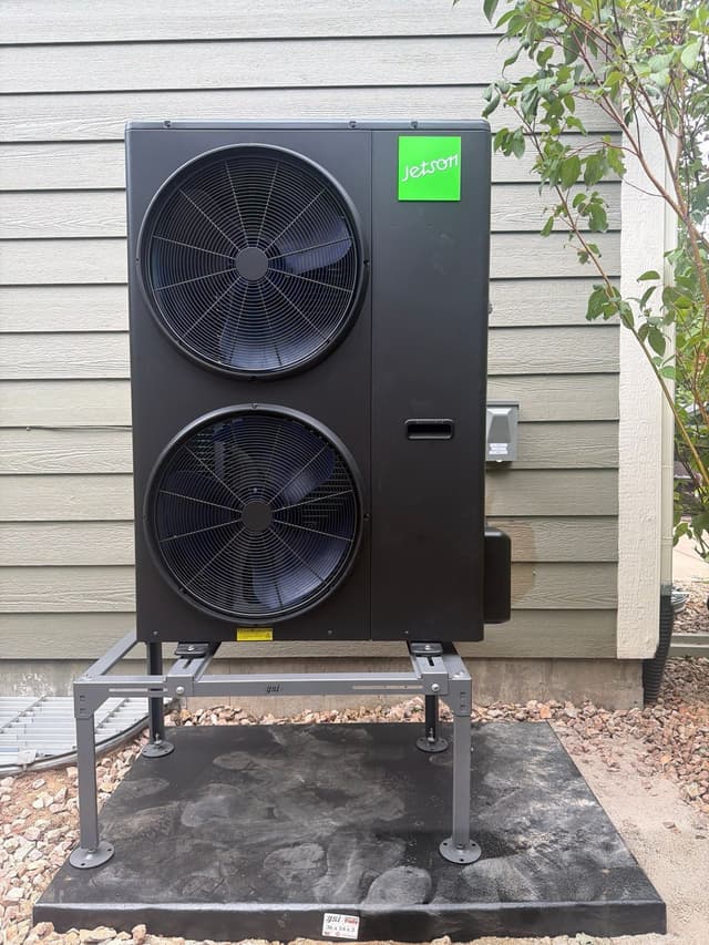 Jetson Air 4-ton dual-fan heat pump outdoor unit installed against house siding with gravel landscaping in Brighton, CO.
