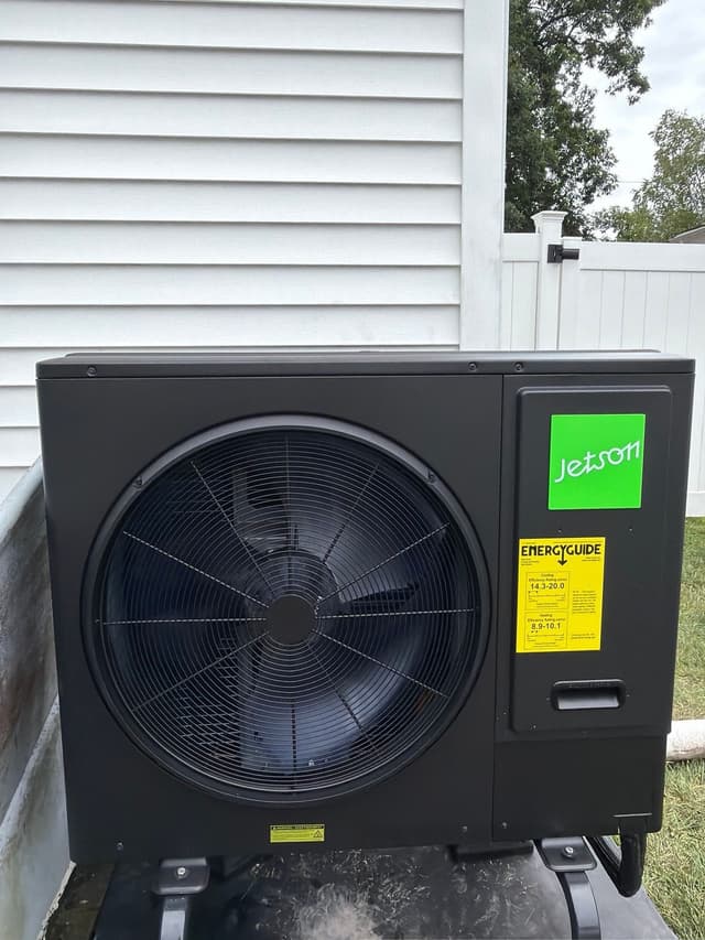 Black Jetson Air 3-ton central ducted heat pump condenser installed beside white vinyl siding at a home in Brockton, MA.
