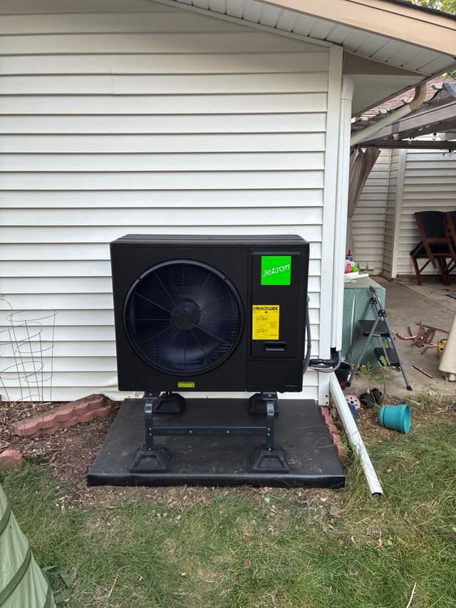Jetson Air 3-ton heat pump mounted on a black riser pad against white vinyl siding on a Broomfield, CO home, with the Jetson logo and EnergyGuide sticker visible.