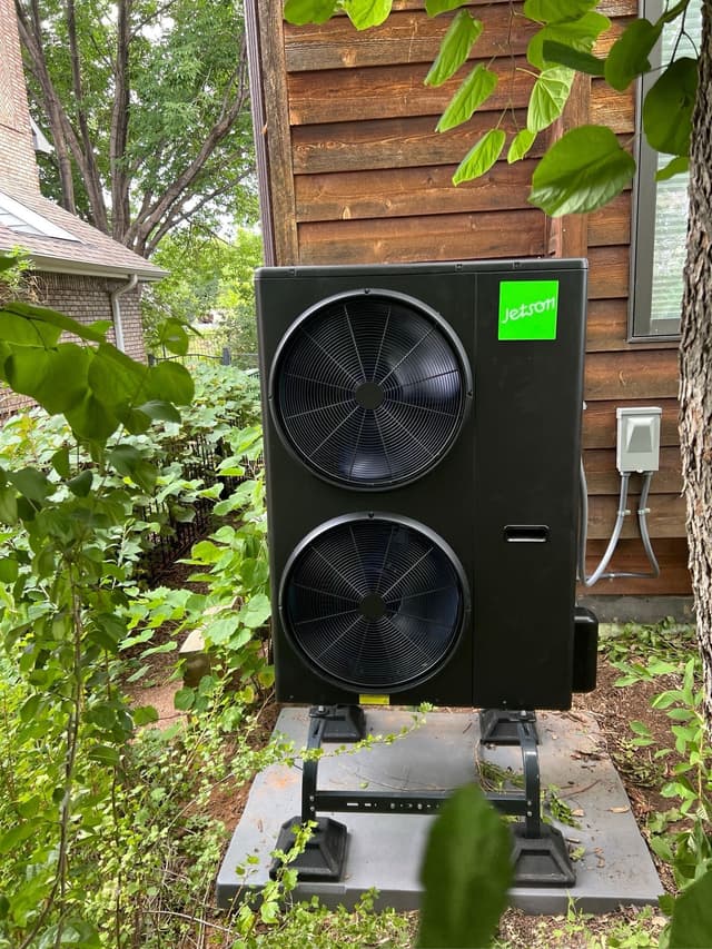 4-ton Jetson Air dual-fan outdoor heat pump condenser installed against dark wood siding in a residential backyard in Fort Collins, Colorado.