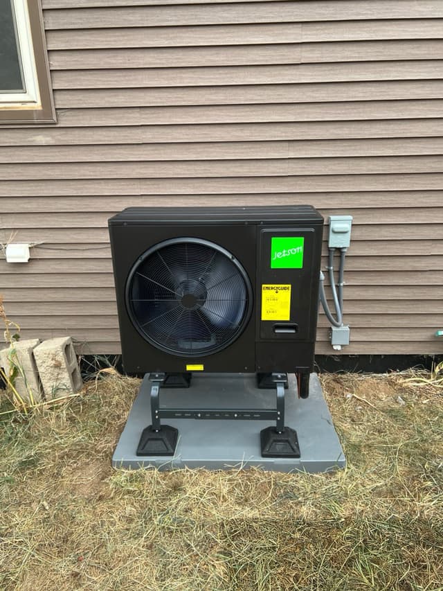 Jetson Air 3-ton central ducted heat pump outdoor unit installed against grey horizontal siding at a Fort Collins home, with electrical disconnect box mounted to the right.