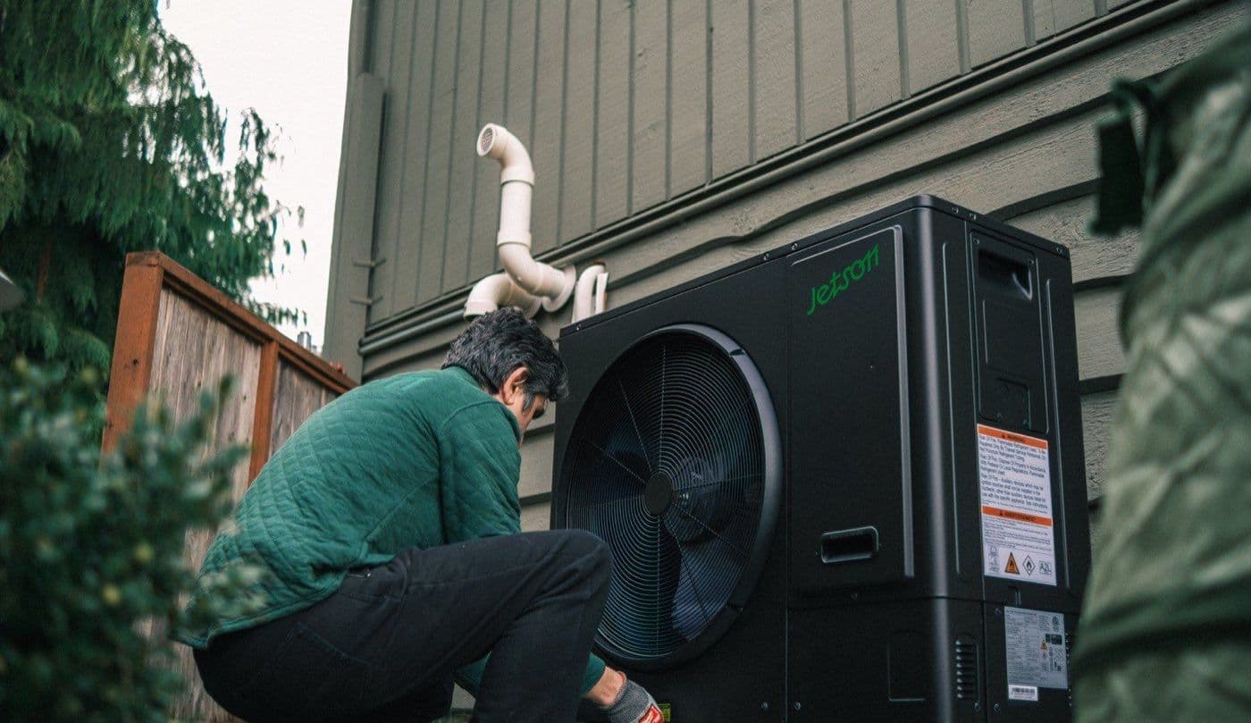 A Jetson technician installing a heat pump condenser at a home