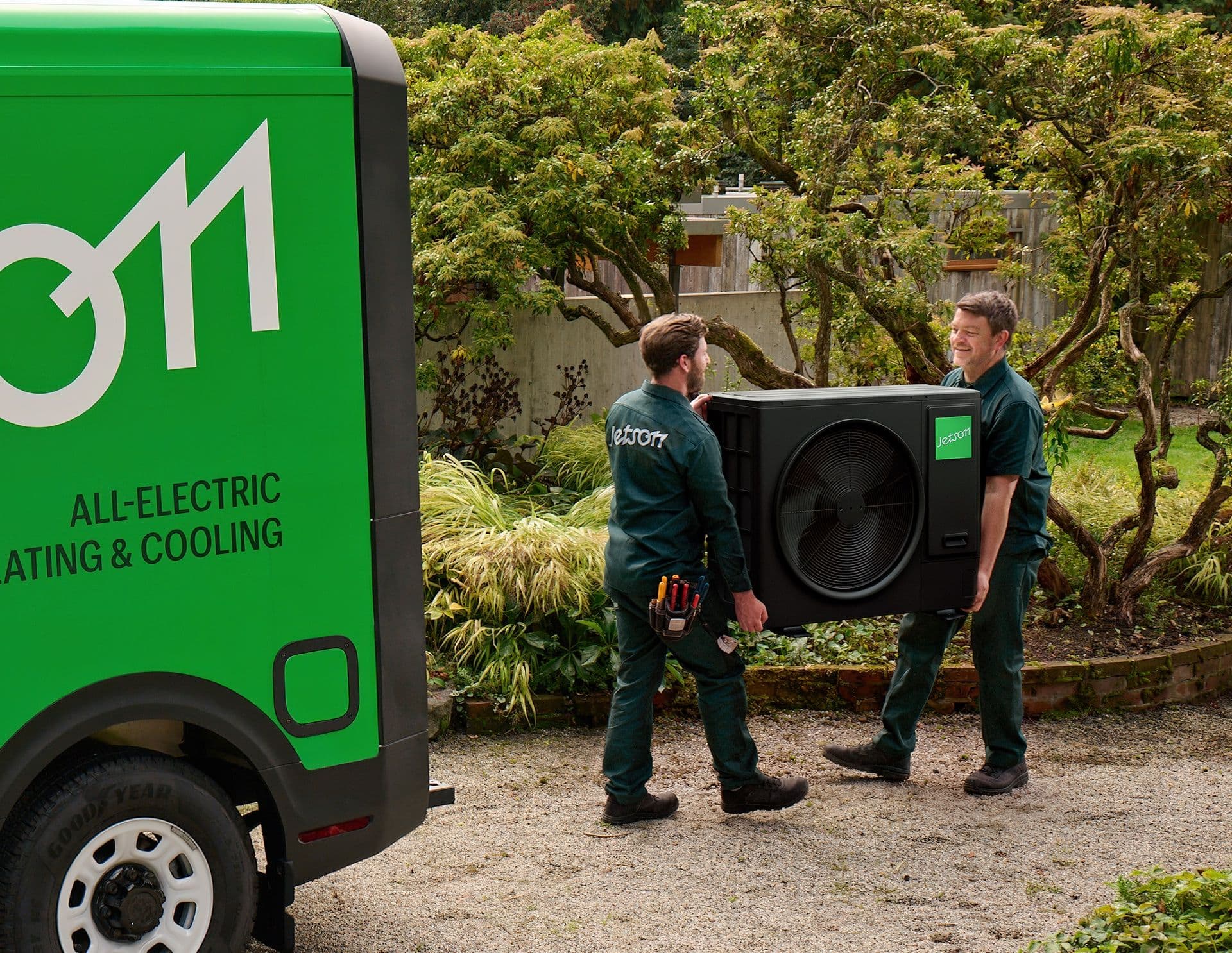Jetson installers carrying heat pump unit next to Jetson van