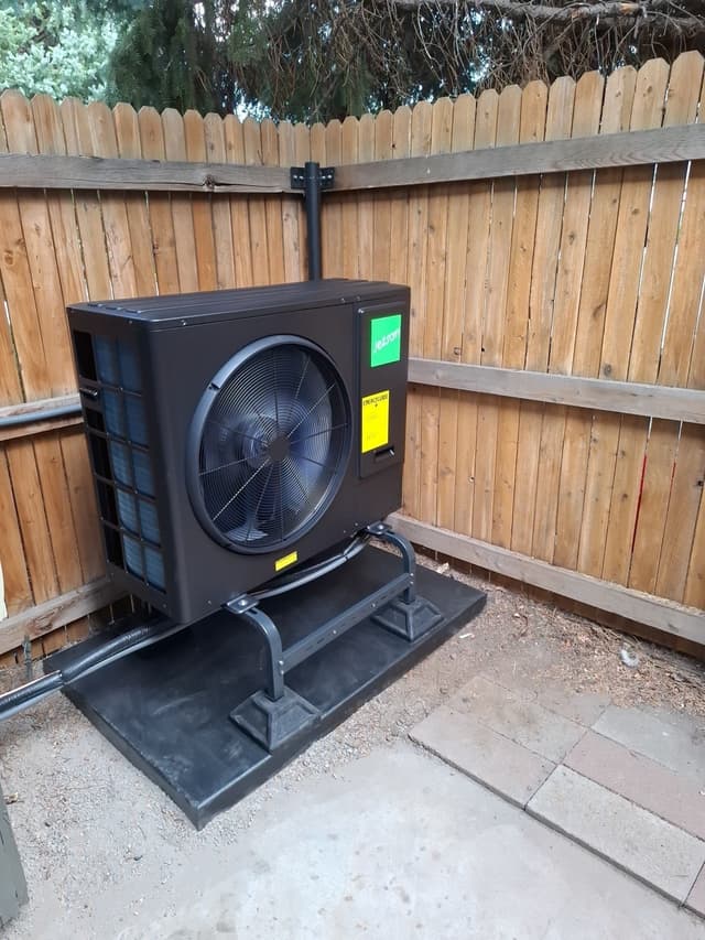 Jetson Air 3-ton heat pump outdoor unit installed in a backyard corner against a wooden privacy fence in Lakewood, CO.