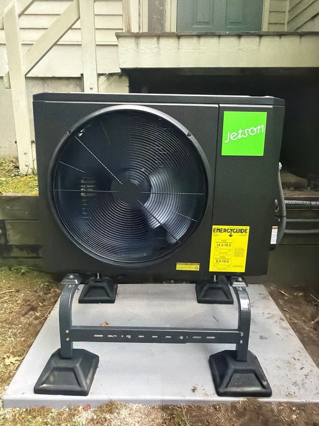 Jetson Air 2-ton heat pump outdoor unit installed at a white-sided home in Lincoln, MA, with the Jetson logo and EnergyGuide sticker visible on the front panel.