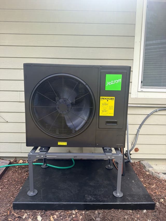 Jetson Air 3-ton central ducted heat pump installed outdoors at a Littleton home, with mulch at ground level and conduit running toward the house siding.