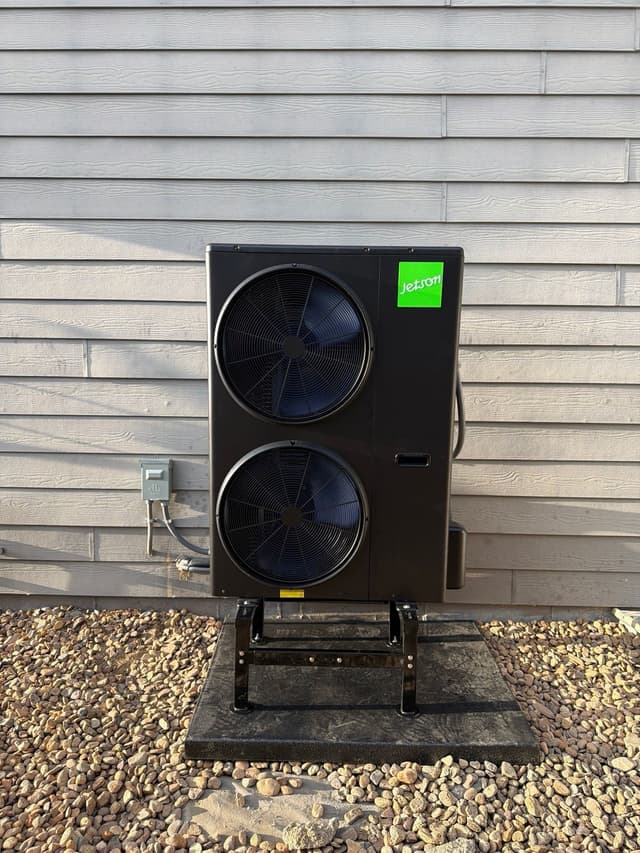 Jetson Air 4-ton dual-fan heat pump condenser installed against gray lap siding at a home in Longmont, Colorado.