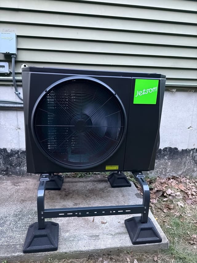 Jetson Air 2-ton central ducted heat pump mounted against green vinyl siding of a home in Northbridge, MA.
