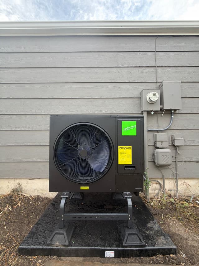 Jetson Air 3-ton central ducted heat pump condenser installed at a Parker, CO home, with gray lap siding and electrical disconnect visible in the background.