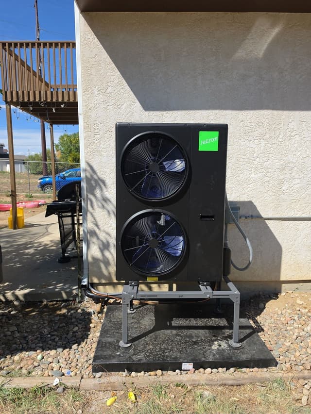 4-ton Jetson Air dual-fan heat pump unit installed against the stucco exterior of a home in Pueblo, Colorado, with river rock landscaping and a covered patio visible nearby.
