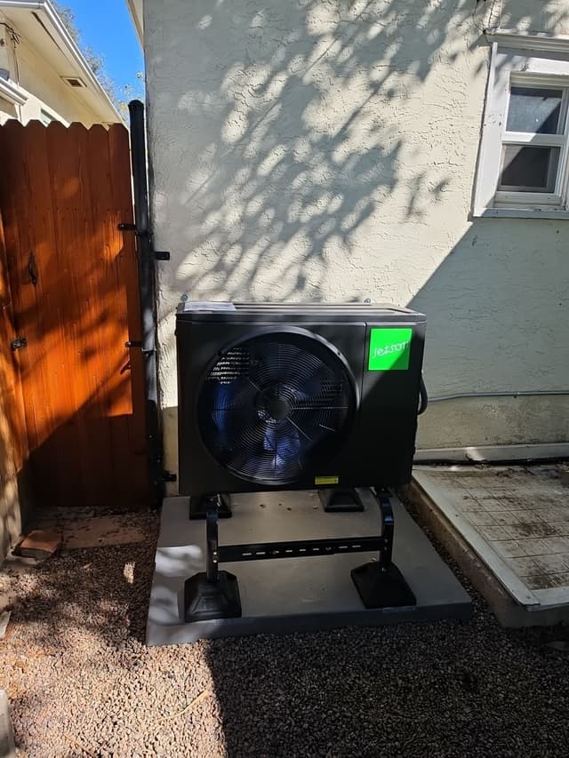 Jetson Air 2-ton central ducted heat pump installed in a gravel side yard against a light stucco exterior wall in Pueblo, CO.