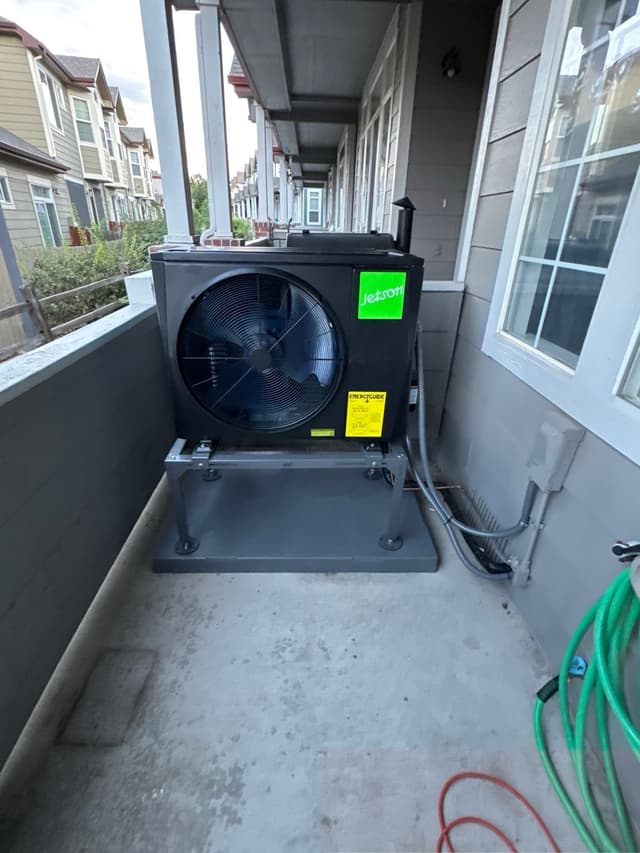 2-ton ducted heat pump installed on a covered concrete balcony of a townhome in Superior, CO, with conduit running neatly along the exterior wall.
